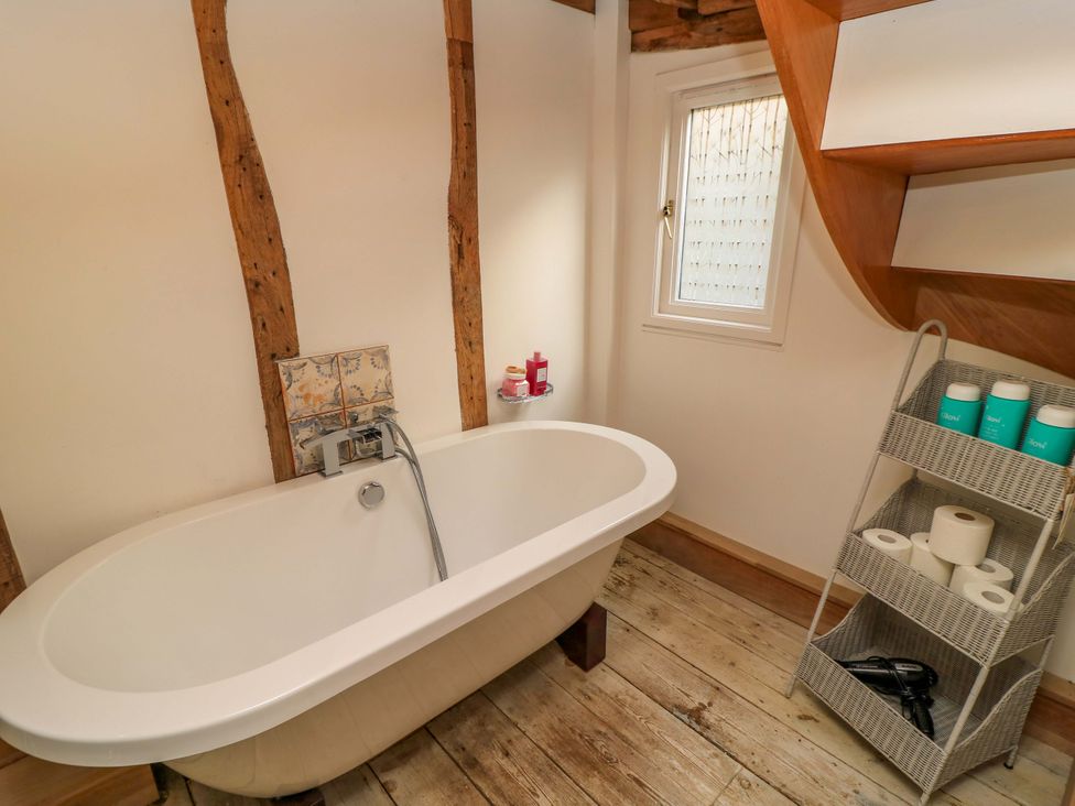A bathroom with a bathtub and shelf at The Linhay in Little Coxwell near Faringdon