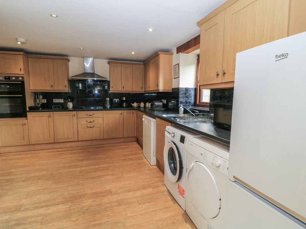 A kitchen with cabinets, a sink, and appliances at Tithe Barn, Lyneham