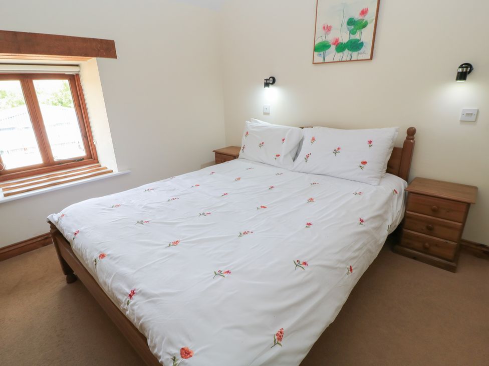 A bedroom with a bed and a window at Tithe Barn, Lyneham
