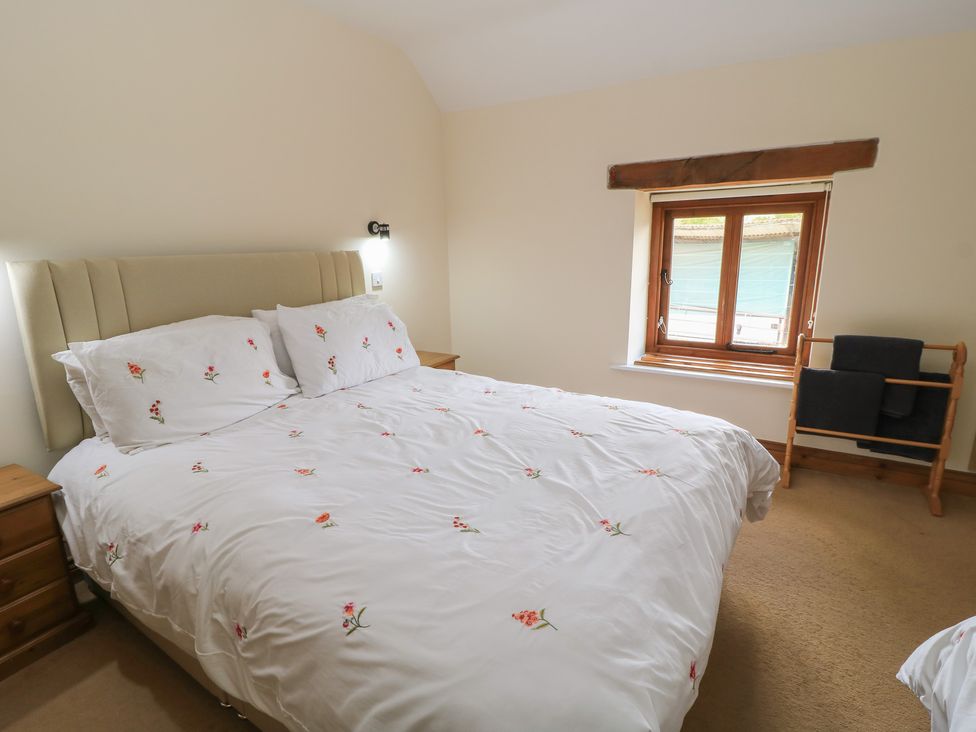 A bedroom with a bed and window at Tithe Barn, Lyneham