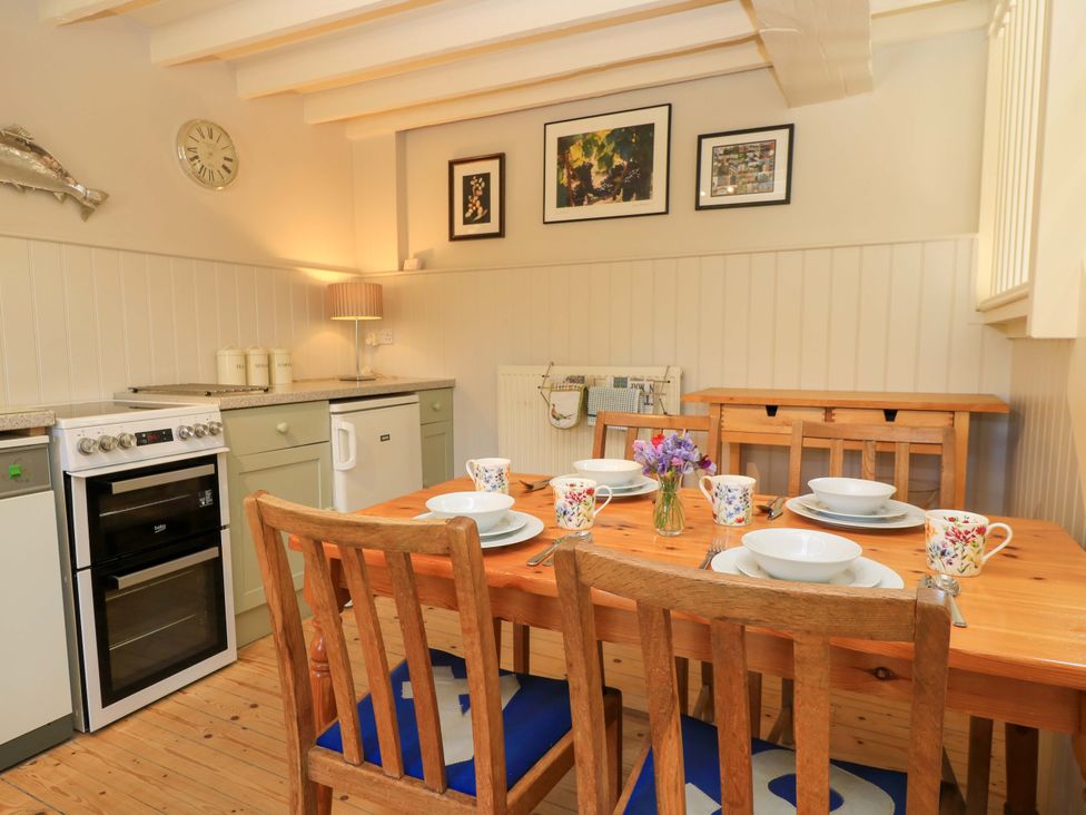 A kitchen with a dining table set with dishes at Cider Press Cottage in Priston Village, Bath