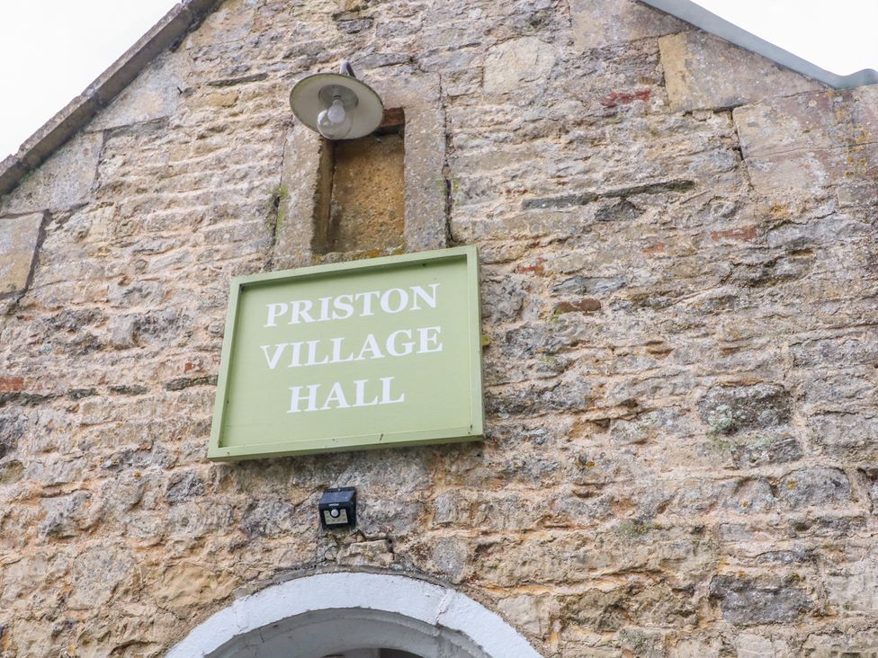 A sign for Priston Village Hall on a stone wall at Cider Press Cottage Priston Village, Bath