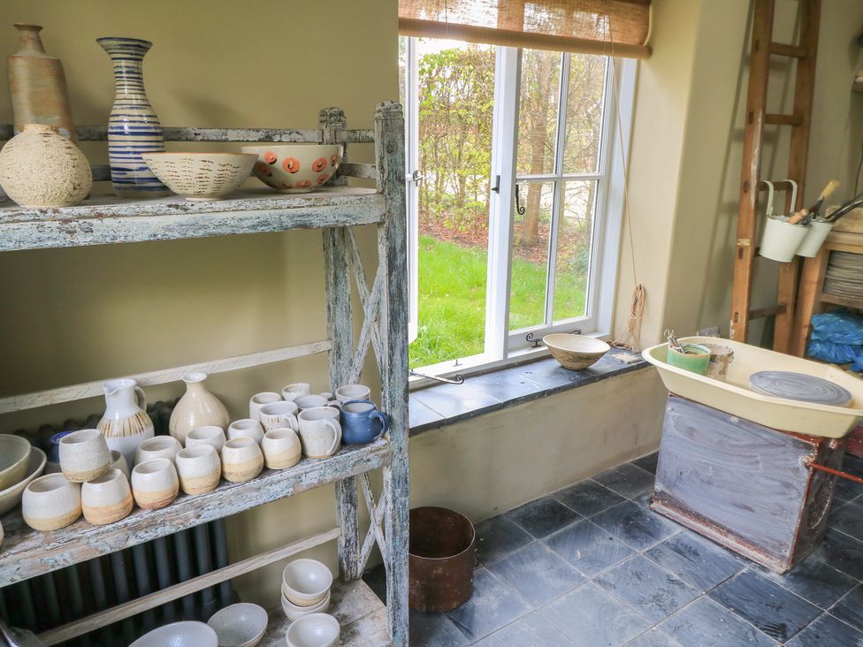A kitchen with pottery on a shelf and a sink at Bridge Studio Near Broad Chalke