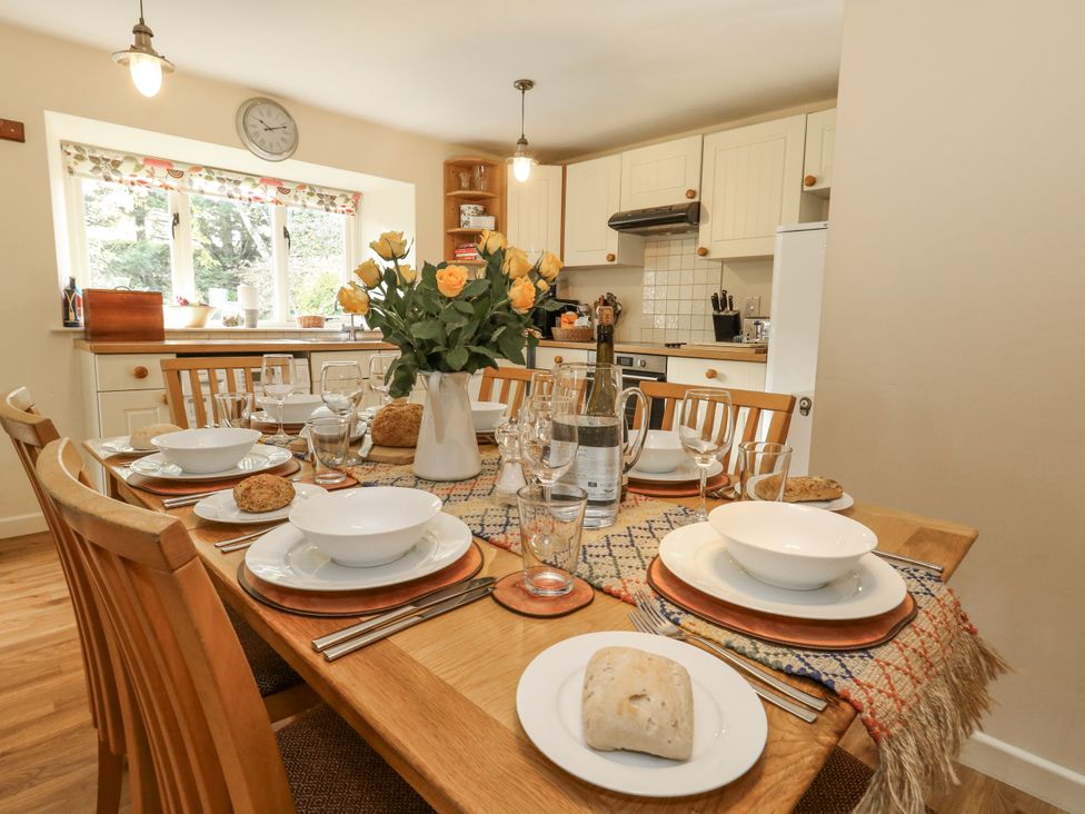 A dining table set with dishes and flowers at Droop Farm Cottage in Droop near Hazelbury Bryan