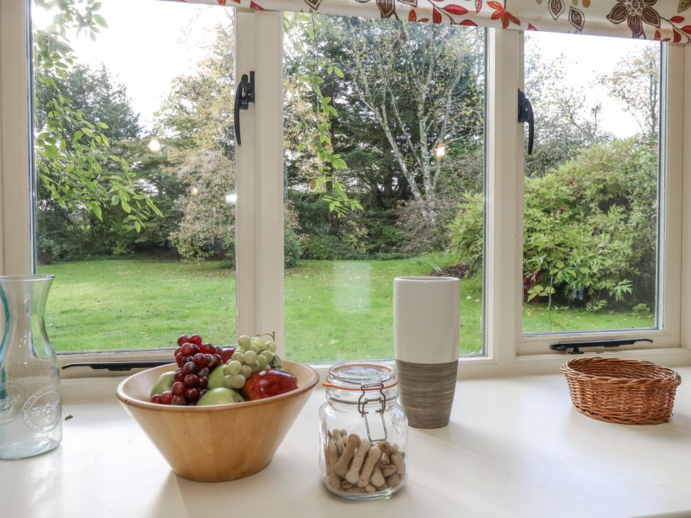 A kitchen with a garden view featuring fruit in a bowl and a vase at Droop Farm Cottage in Droop near Hazelbury Bryan