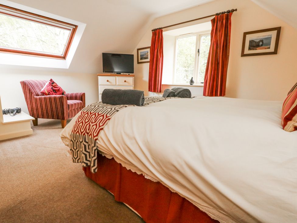 A bedroom with a bed and chair at Droop Farm Cottage in Droop near Hazelbury Bryan