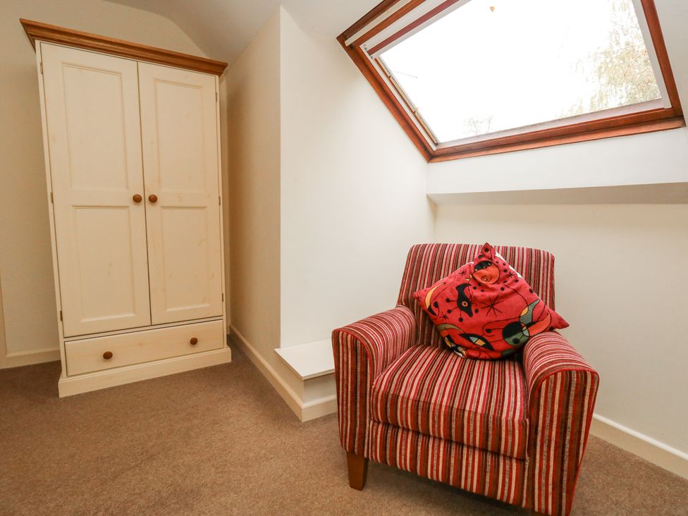 A bedroom with a wardrobe and armchair at Droop Farm Cottage Droop near Hazelbury Bryan