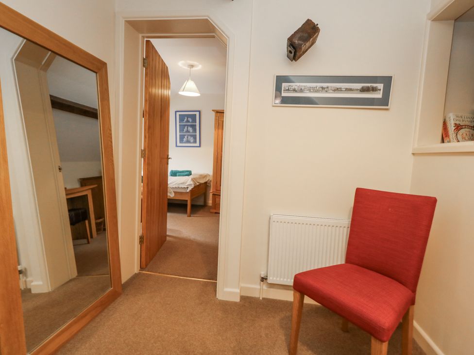 A hallway with a chair, mirror, and framed picture at Droop Farm Cottage, Droop near Hazelbury Bryan