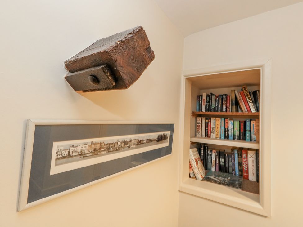A bookshelf with books and a framed picture at Droop Farm Cottage in Droop near Hazelbury Bryan
