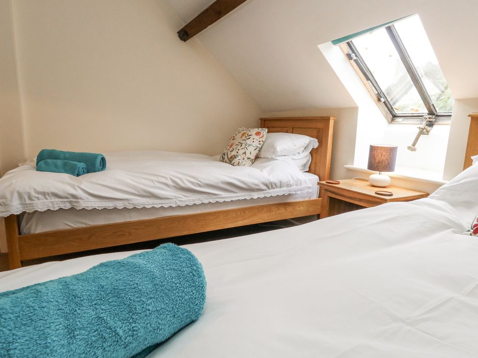 A bedroom with two beds and a window at Droop Farm Cottage near Hazelbury Bryan