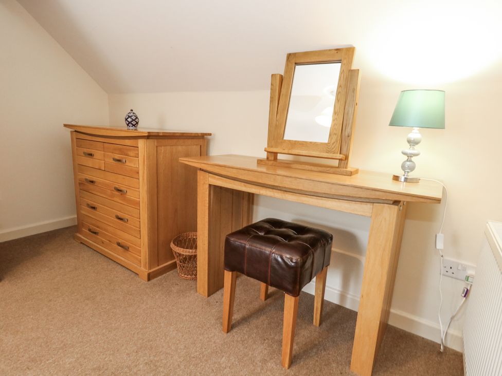 A bedroom with a dresser, table, mirror and lamp at Droop Farm Cottage Droop near Hazelbury Bryan