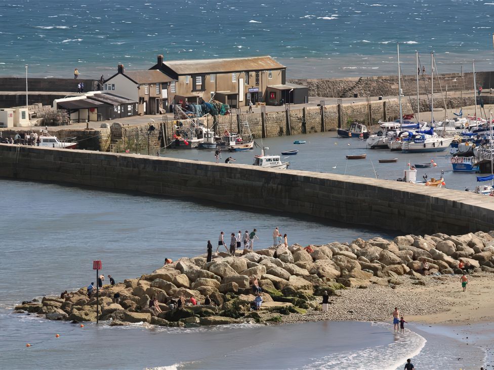 A harbor with boats and people on a rocky shore at Droop Farm Cottage in Droop near Hazelbury Bryan