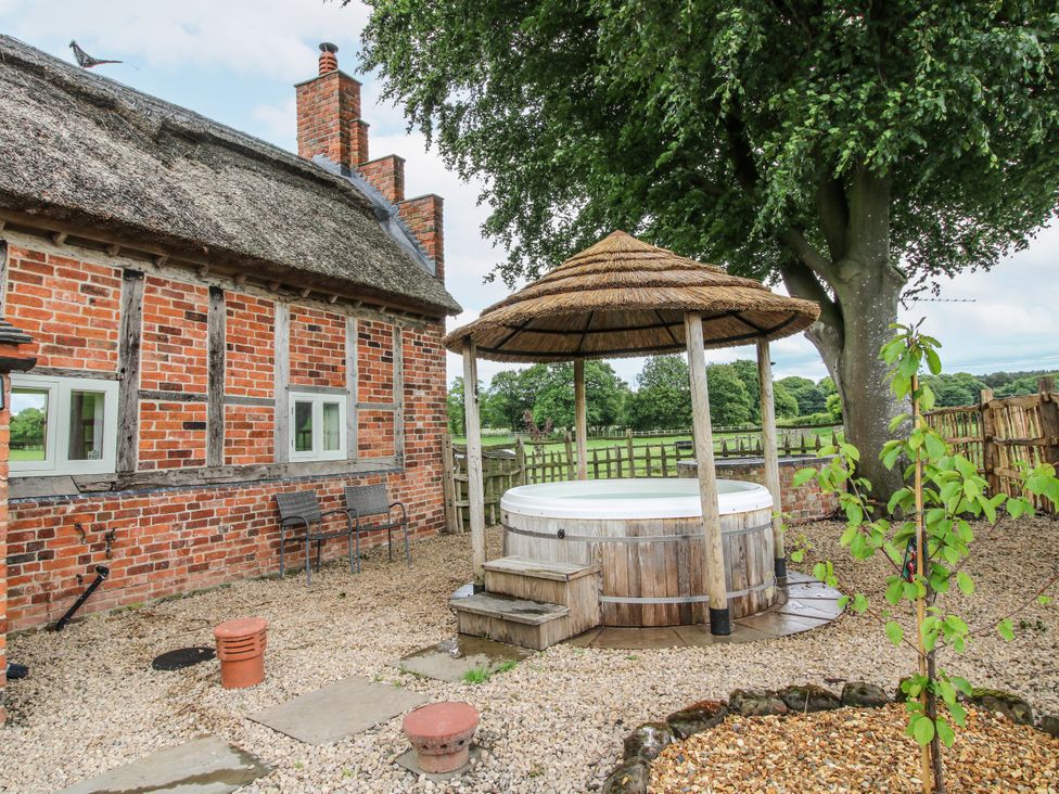 An outdoor area with a hot tub and seating at The Shooting Folly in Cheswardine