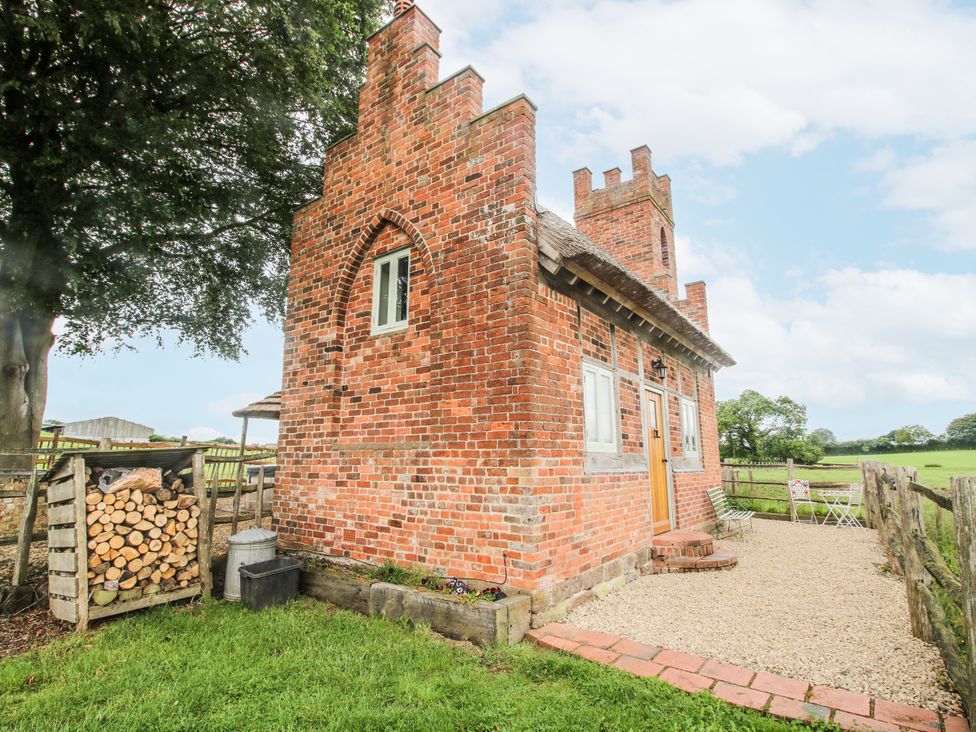 A brick building with a wooden door and stone pathway at The Shooting Folly in Cheswardine