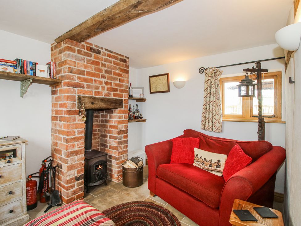 A snug with a brick fireplace and couch at The Shooting Folly in Cheswardine