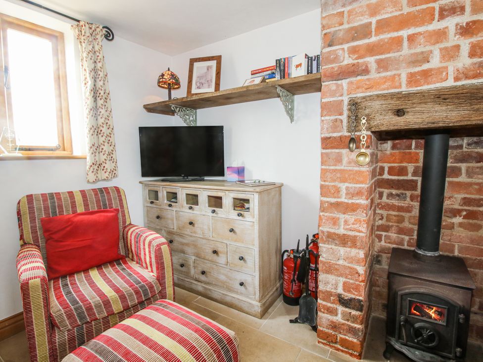 A living room with a television and wooden furniture at The Shooting Folly in Cheswardine