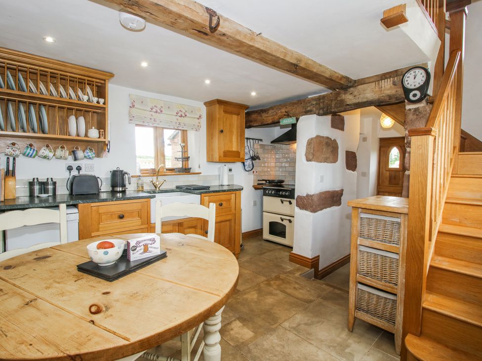 A kitchen with wooden cabinets and table at The Shooting Folly in Cheswardine
