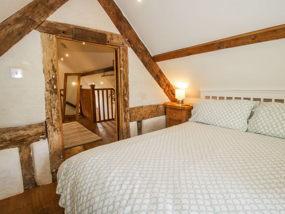 A bedroom with a bed and a door leading to a staircase at The Shooting Folly in Cheswardine