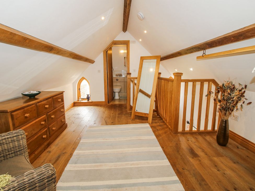 A loft area with wooden furniture and bathroom access at The Shooting Folly in Cheswardine