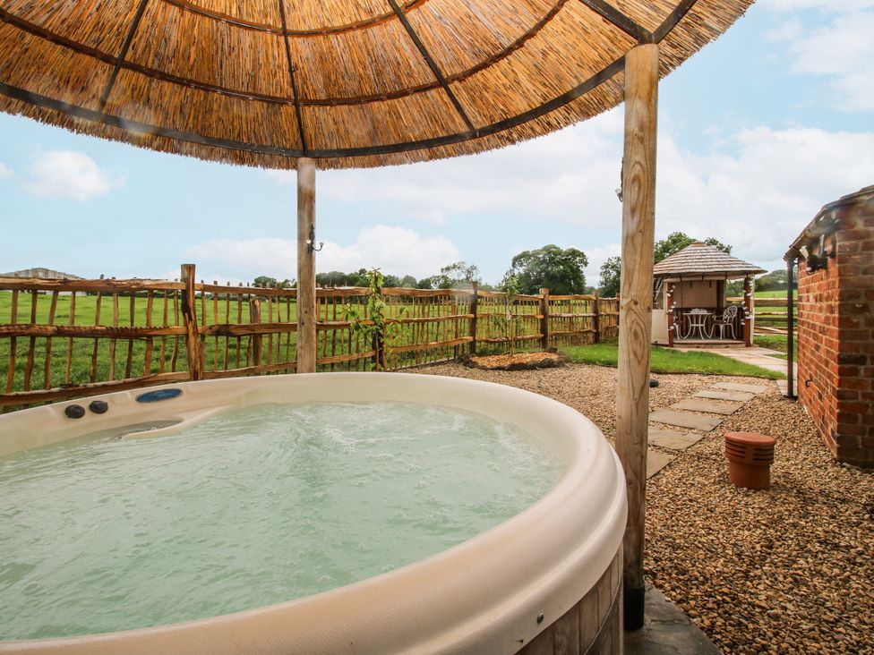 A hot tub with a thatched roof and a garden house at The Shooting Folly in Cheswardine