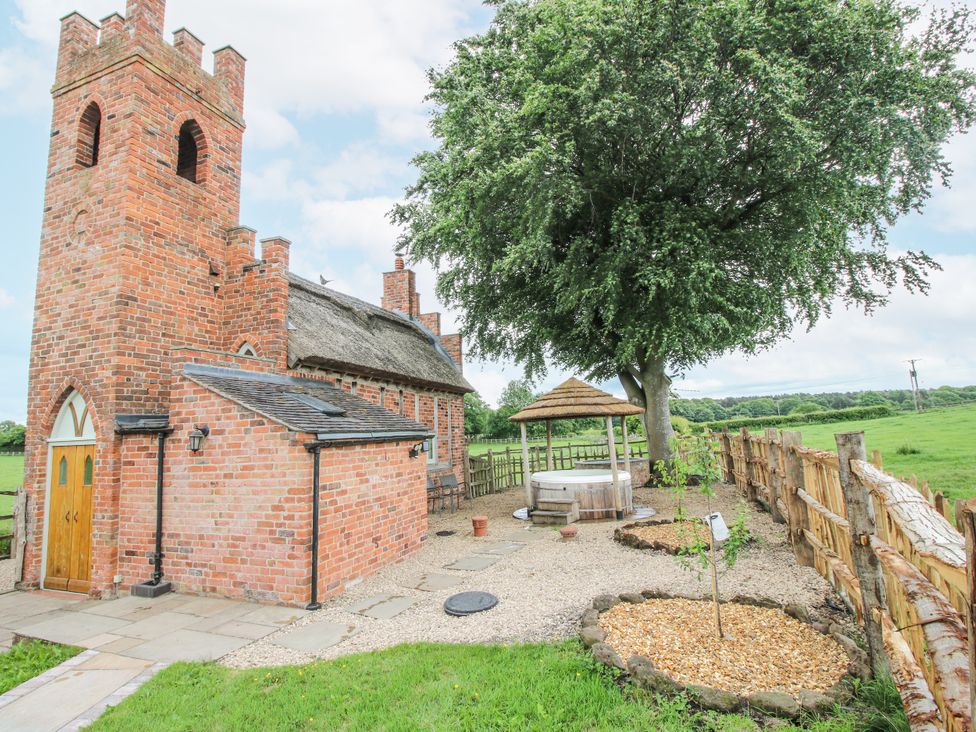 A building with a thatched roof and chimney in a garden area at The Shooting Folly in Cheswardine