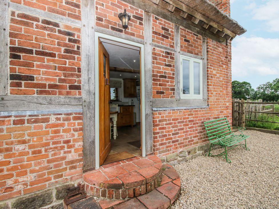 An entrance to a property with a wooden door and a green bench at The Shooting Folly in Cheswardine