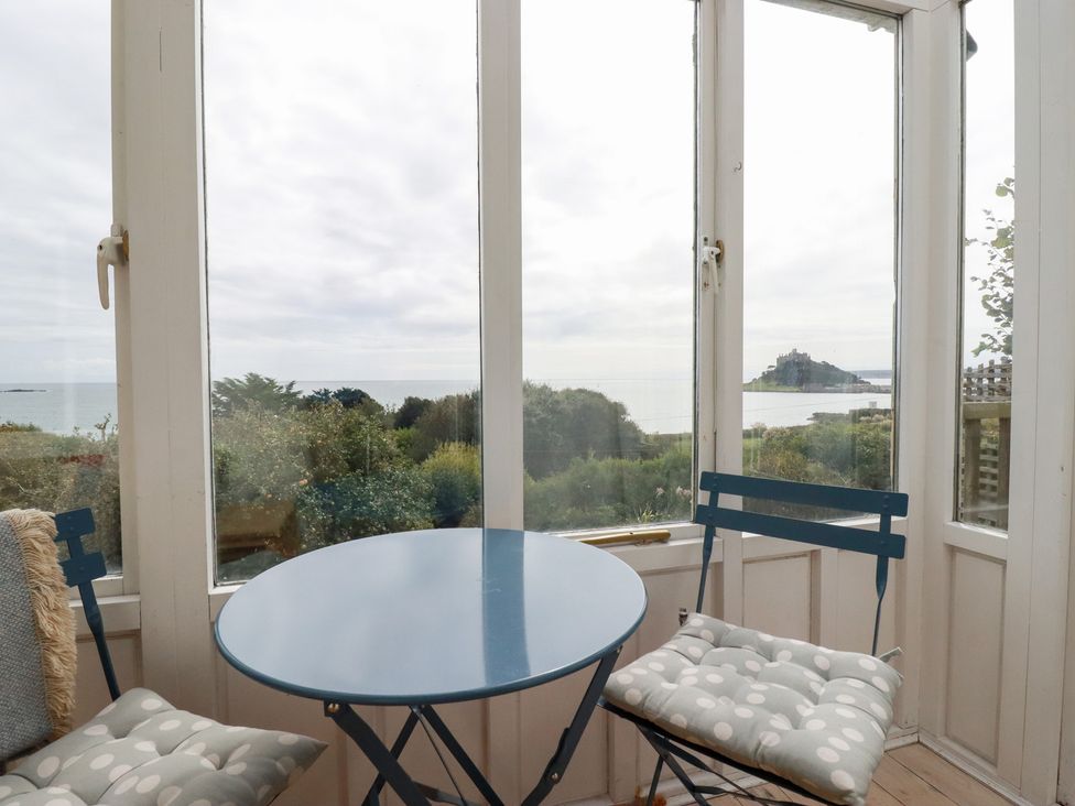 A table and chairs in a conservatory with a sea view at Greeb Rocks Cottage Marazion