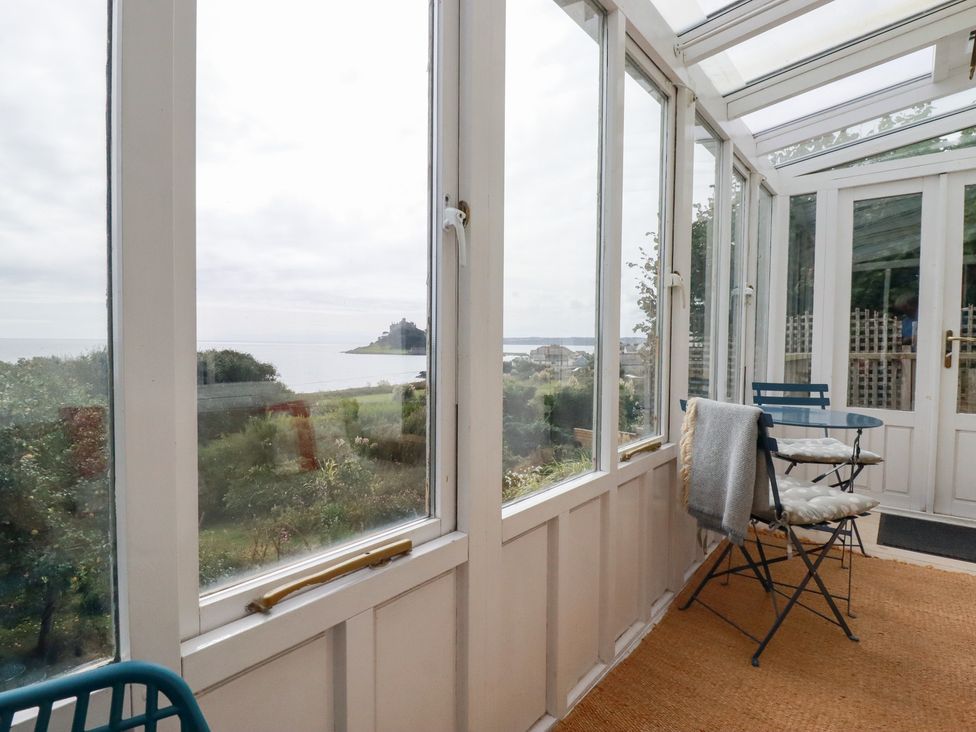 A conservatory with chairs and a view at Greeb Rocks Cottage Marazion