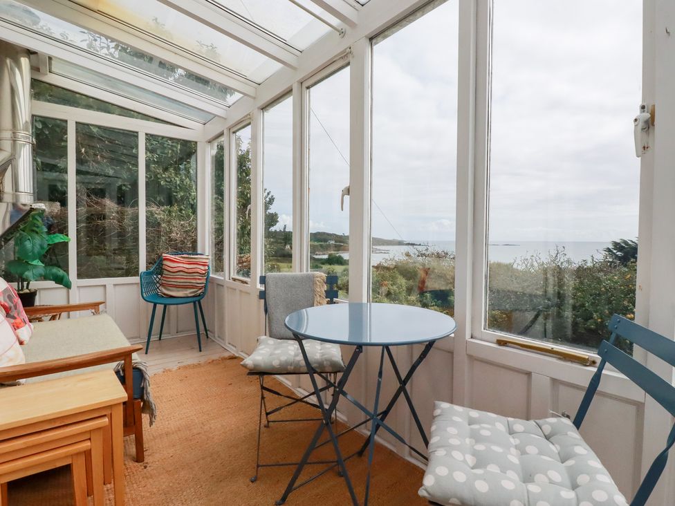 A conservatory with a table and chairs at Greeb Rocks Cottage in Marazion
