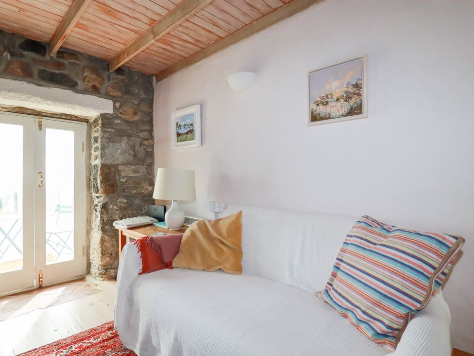 A living room with a sofa and a door to the outside at Greeb Rocks Cottage in Marazion