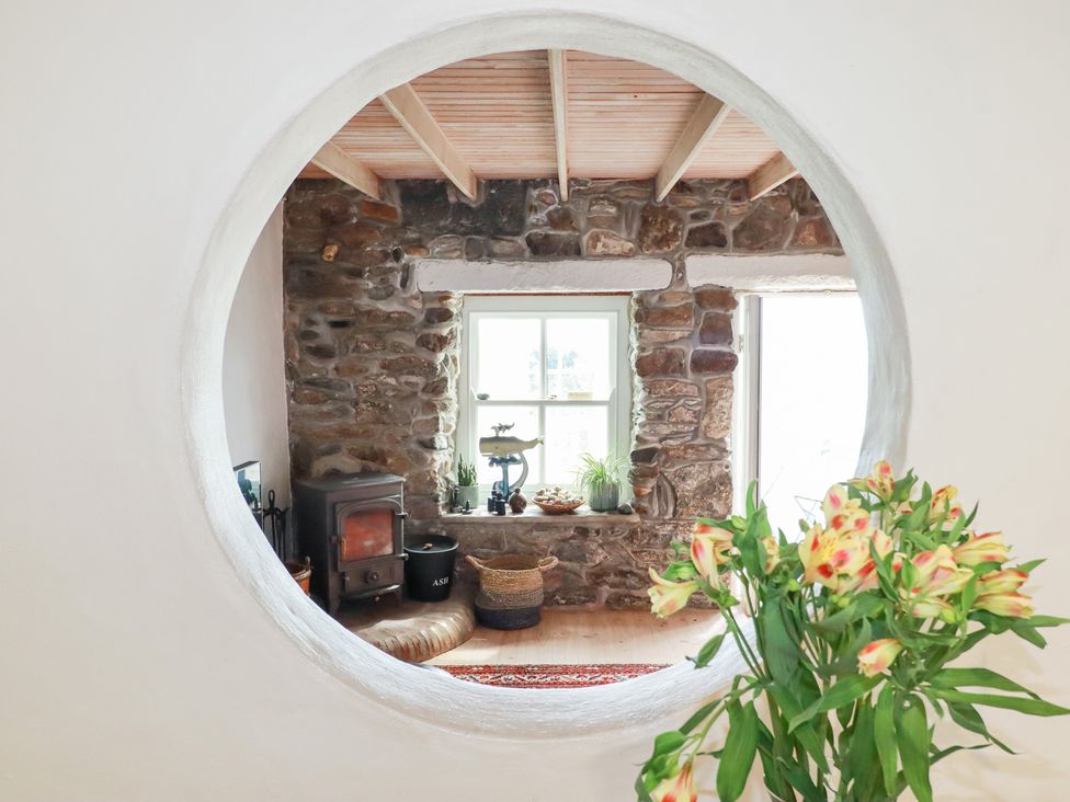 A living room with a stone wall and wood stove at Greeb Rocks Cottage in Marazion