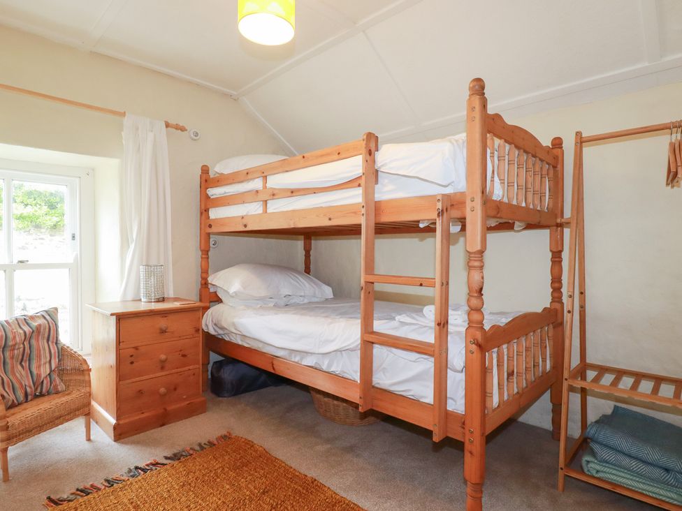 A bedroom with a bunk bed and a nightstand at Greeb Rocks Cottage in Marazion