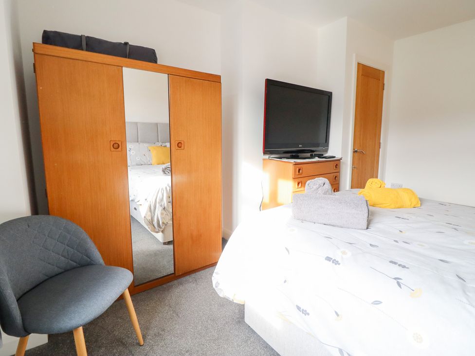 A bedroom with a bed, television, wardrobe and chair at Arnant in Dolgellau