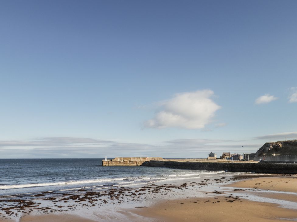 A beach with sand and buildings along the shore at 83 Seatown in Cullen