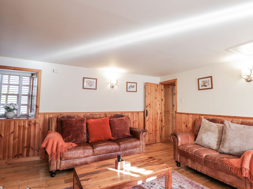 A living room with brown sofas and a wooden table at 83 Seatown in Cullen