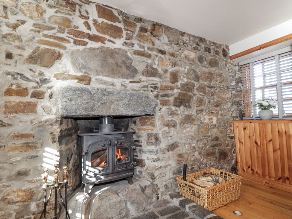 A living room with a stone wall and wood stove at 83 Seatown, Cullen