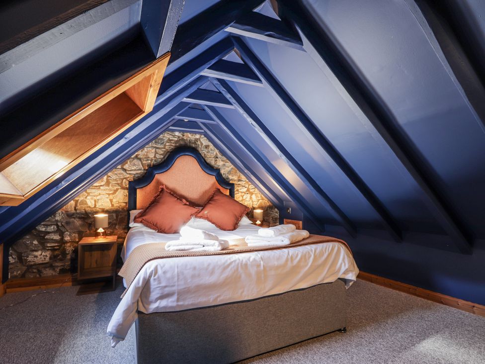 A bedroom with a bed and stone wall at 83 Seatown, Cullen