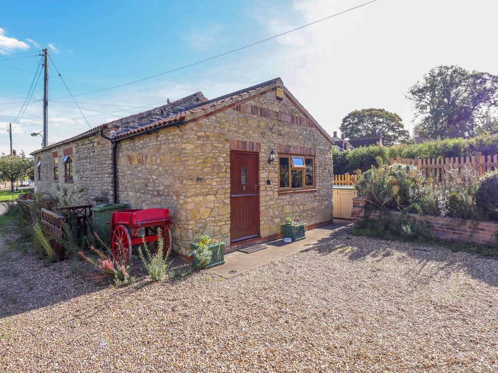 An outdoor view of a stone cottage with a gravel driveway at The Barn in Snitterby