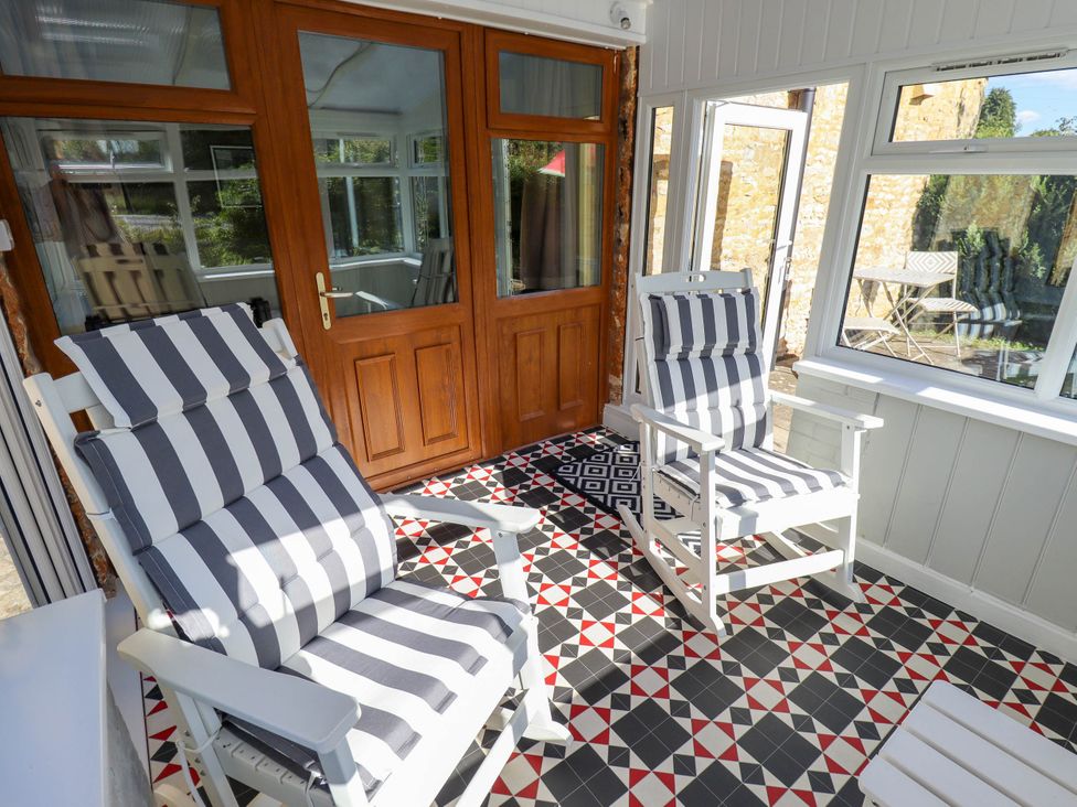 A conservatory with rocking chairs and tiled floor at The Barn in Snitterby