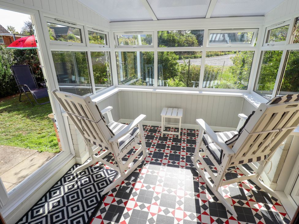 A conservatory with rocking chairs and a table at The Barn in Snitterby