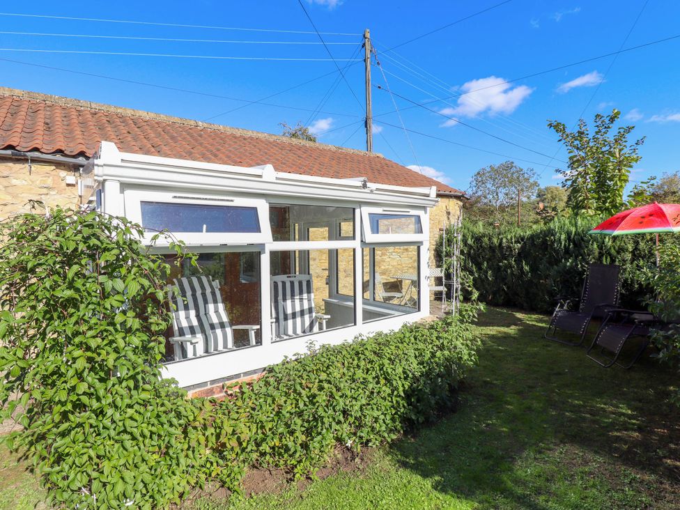 A conservatory with chairs and a table in the garden at The Barn Snitterby