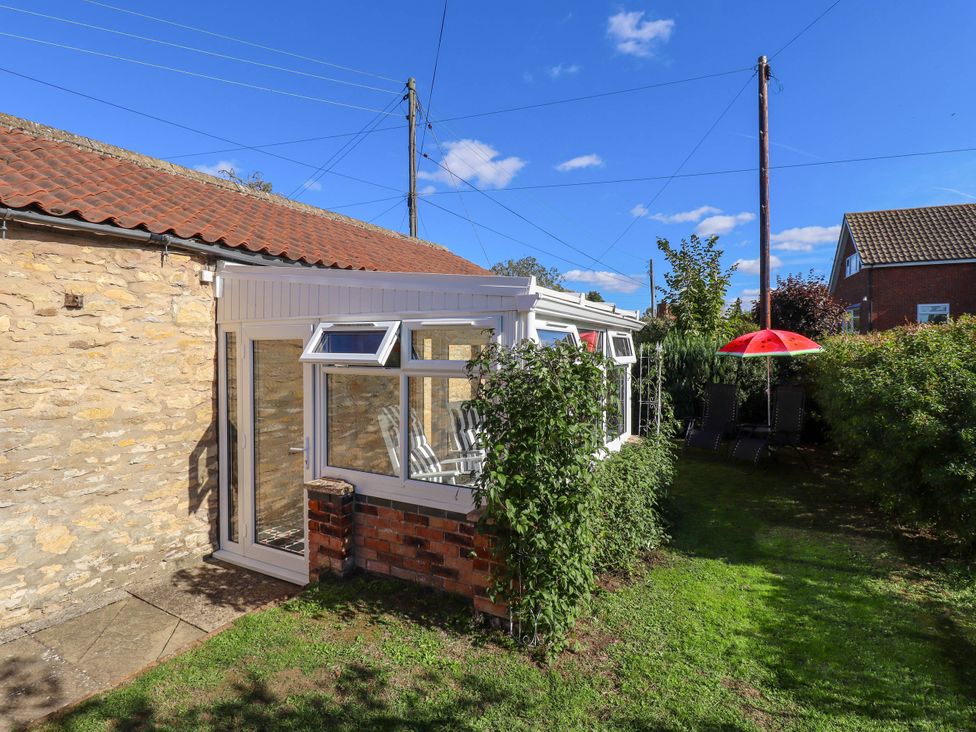 A garden with a conservatory and umbrella at The Barn in Snitterby