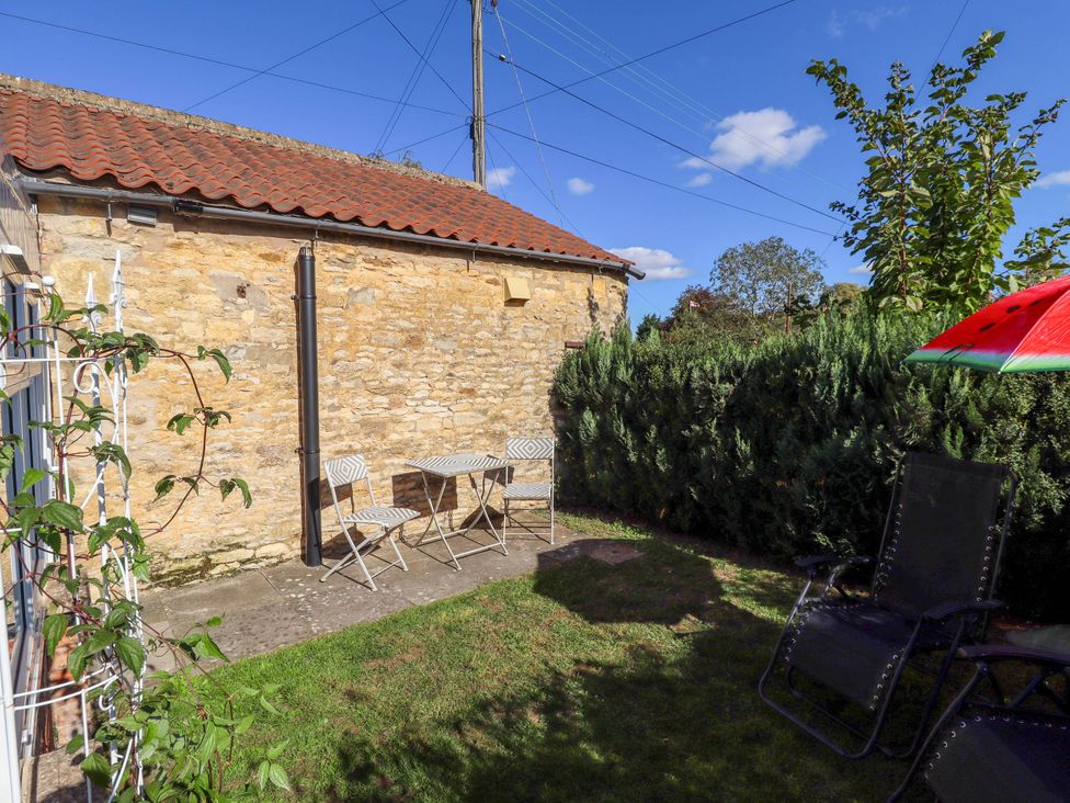 A garden with a table and chairs by a stone wall at The Barn in Snitterby