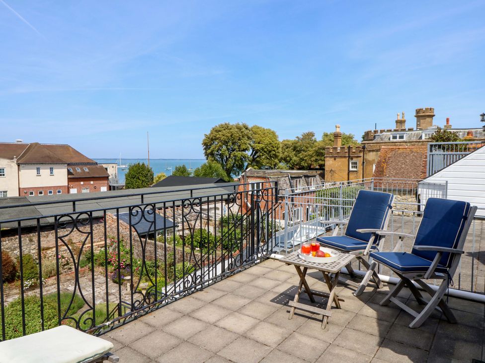 A balcony with chairs and a table overlooking the sea at Tovah in Yarmouth
