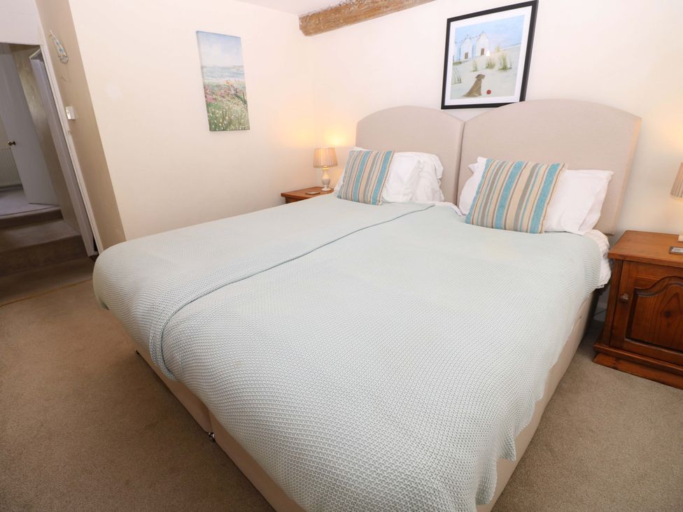 A bedroom with a bed, nightstand, lamp and painting at Tovah in Yarmouth