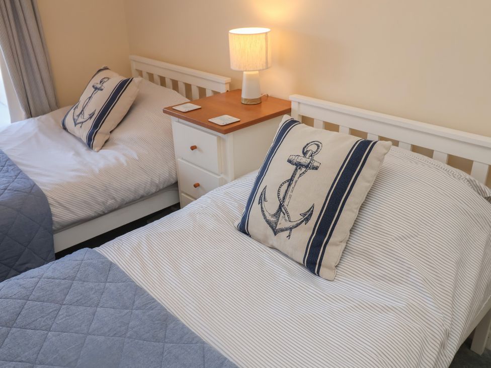 A bedroom with two beds and a lamp on a nightstand at Daisy Lodge in Norwich