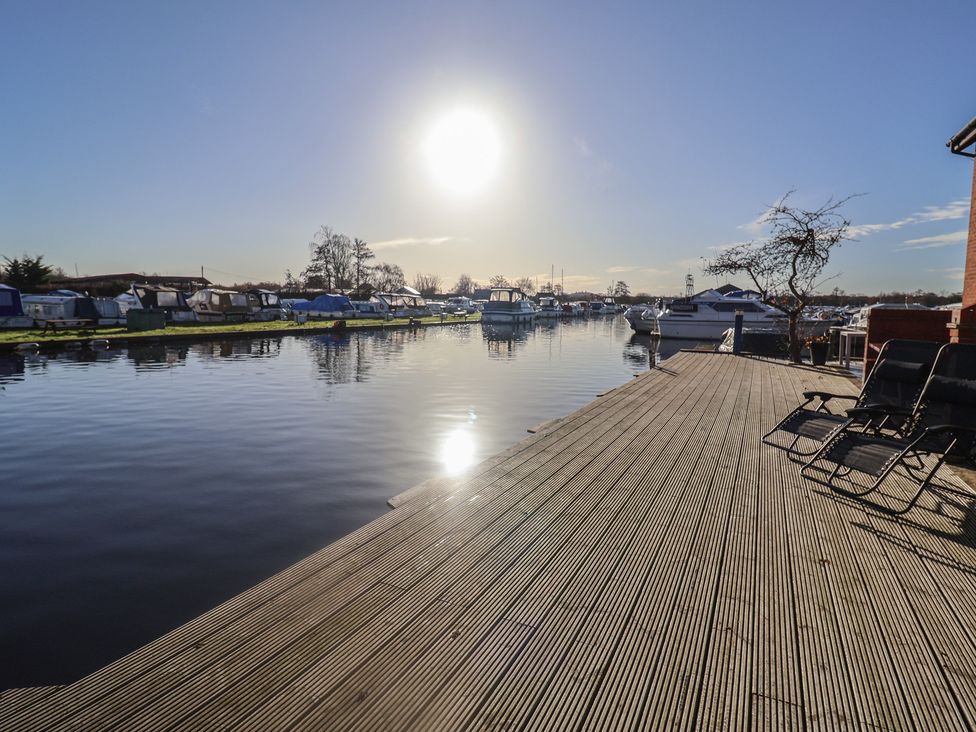 A dock with boats reflecting in the water at Daisy Lodge in Norwich