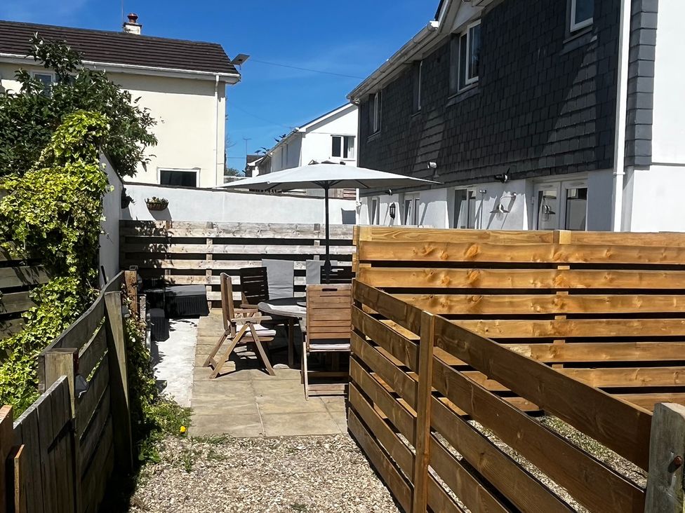 A garden with seating area and wooden fence at 8 Harlyn Mews Harlyn Bay, Cornwall