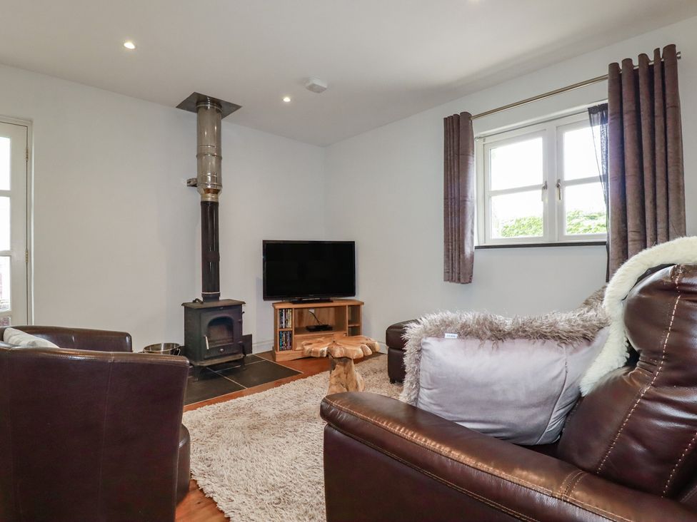 A living room with a wood stove and television at The Smithy in Blisland