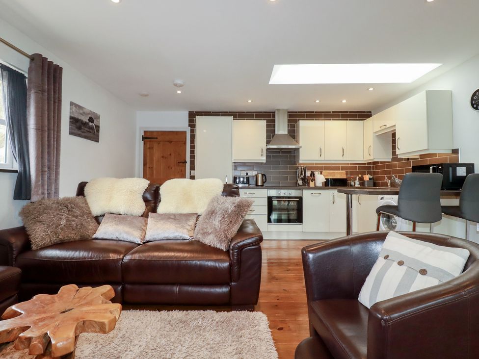 A living room with a sofa and kitchen area at The Smithy in Blisland